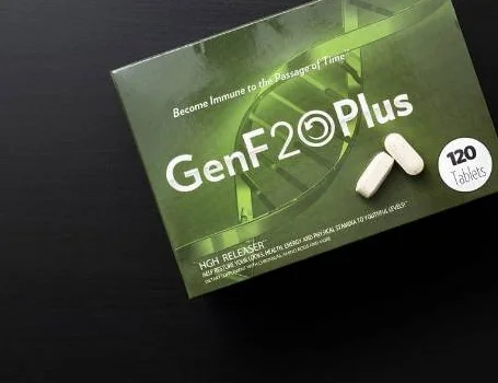 The GenF20 Plus box tilted on a plain black surface with two white tablets resting on top of it